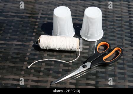 Cups String Schere - ein Telefon aus Plastikbecher und -Schnur machen, Wissenschaft experimentieren zu Hause mit Schallwellen und Vibrationen Stockfoto