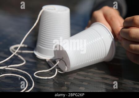 Ein Telefon aus Plastikbechern und Schnüren, School Science Experiment at Home mit Schallwellen und Vibrationen, Großbritannien Stockfoto