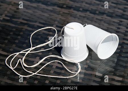 Ein Telefon aus Plastikbechern und String, Heimschule Wissenschaft Experiment mit Schallwellen und Vibrationen, Großbritannien Stockfoto