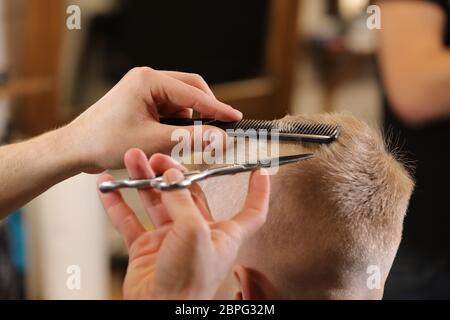 Frisur, Friseursalon für Herren. Nahaufnahme von Mann Hände Pflege Kind Jungen Haare im Friseur. Porträt des männlichen Kindes bei Stockfoto