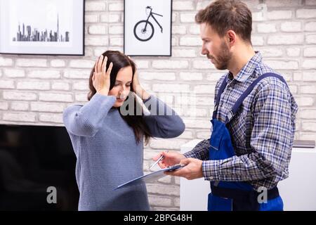 Schockiert Frau auf der Suche nach Rechnung von männlichen Techniker Stockfoto