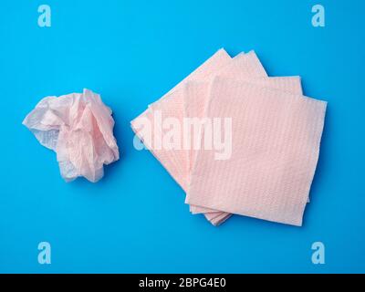 Zerknitterte rosa Papier Einweg Servietten auf blauem Hintergrund, Draufsicht Stockfoto