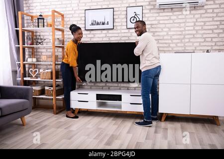 Seitenansicht des jungen afrikanischen Paar heben Fernsehen zu Hause Stockfoto