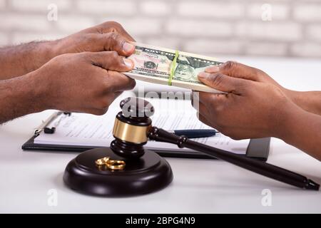 In der Nähe von Mann und Frau, die für Geld mit Hammer und Goldene Ringe auf Schreibtisch Stockfoto