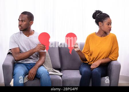 Paar sitzt auf einem Sofa ignorieren Einander und halten Gebrochenes Herz Stockfoto