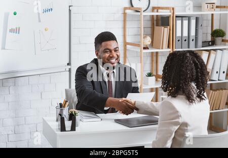 Personalmanager und junger Bewerber schütteln die Hände in modernen Firmenbüro Stockfoto