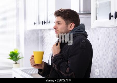 Mann mit Schal um den Hals Leiden unter Kälte Holding Tasse Kaffee Stockfoto