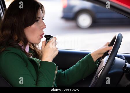 Seitliche Sicht auf eine schöne junge Frau sitzt im Auto, Alkohol Test Stockfoto