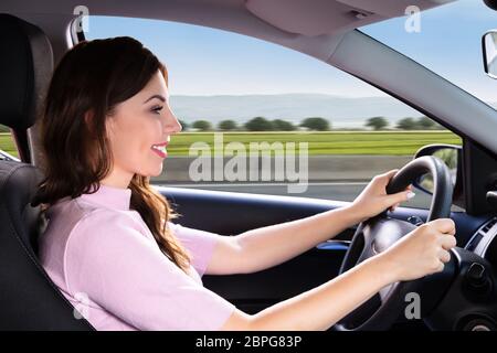 Seitenansicht einer jungen Frau, die mit dem Auto anreisen, Stockfoto