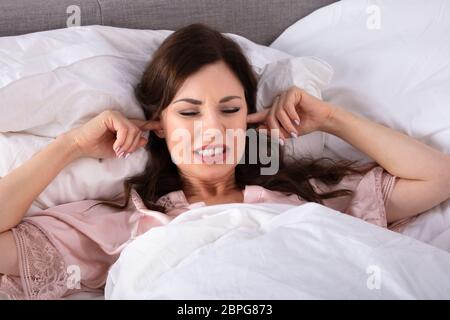 Young Woman Disturbed By Noise Covering Her Ears With Finger Stockfoto