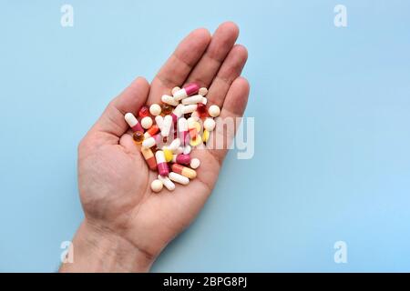 Mehrere Farben Pillen in der Hand auf blauem Hintergrund. Draufsicht Stockfoto