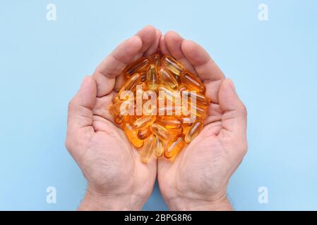 Vitaminen Omega 3 Fischöl in Kapseln auf den Händen auf blauem Hintergrund. Draufsicht Stockfoto