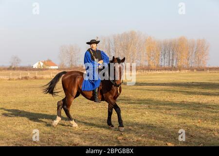 HORTOBAGY, UNGARN, NOVEMBER 04. 2018: Ungarische Csikos in traditioneller Tracht zeigen sein ausgebildetes Pferd. Traditioneller Pferdeherber von Hung Stockfoto