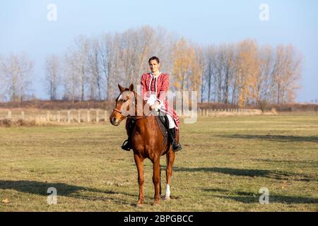 HORTOBAGY, UNGARN, NOVEMBER 04. 2018: Ungarische Csikos-Frau in traditioneller Tracht auf ihrem trainierten Pferd. November 04. 2018, Hortobagy, Hun Stockfoto