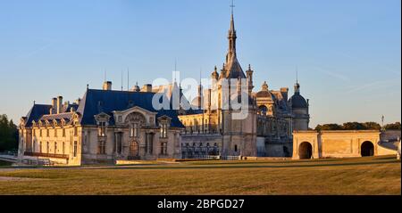 Schloss Chantilly und Museum von Conde bei Sonnenuntergang in Frankreich. Weitwinkelaufnahme Stockfoto