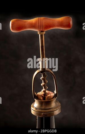 Ein vintage Korkenzieher, zieht einen Korken aus einer Flasche auf schwarzem Hintergrund Stockfoto