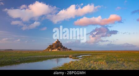 Panoramablick auf den berühmten Mont Saint Michel bei Sonnenuntergang mit Spiegelung im Kanal auf den Wasserwiesen, Normandie, Frankreich Stockfoto