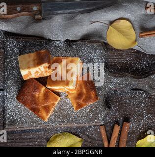 Quadratische Scheiben von Hüttenkäse und Pumpkin Pie auf einem Holzbrett, Dessert ist bestreut mit Puderzucker, Ansicht von oben Stockfoto