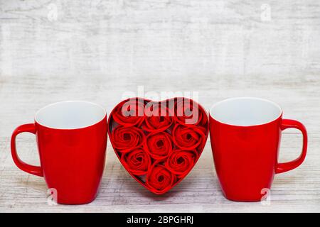 Shiny Red Kaffeetasse und rote Herzrosen zum Valentinstag Stockfoto