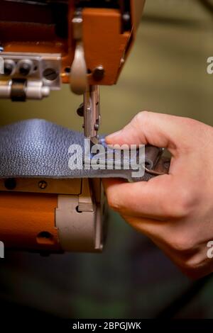 Vertikale Aufnahme des Nähens eines kompletten Box-Stichmusters auf schwarzem Leder Stockfoto