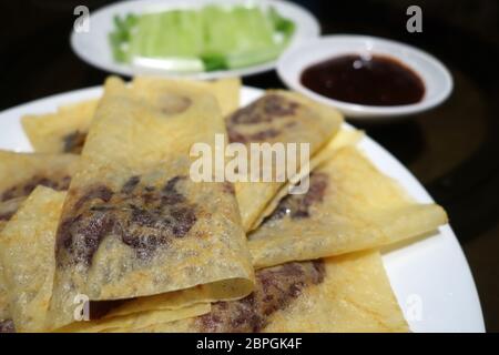 Chinesische Ente mit Gurke, Frühlingszwiebel und Hoisin-Sauce serviert, in Pfannkuchen gewickelt Stockfoto