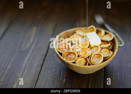 Trendiges Komfortessen - kleine Pfannkuchen, Müsli in Holzschüssel. Serviert mit Butter und Honig Stockfoto
