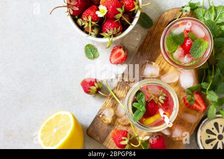 Sommerdrink erfrischend. Limonade mit frischen Erdbeeren, Eis und Zitronen auf einer leichten Steinplatte. Draufsicht flach legen Hintergrund. Kopierbereich. Stockfoto