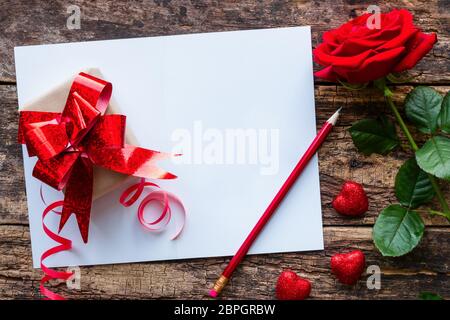 Geschenk, Grußkarte und Strauß roter Rosen am Valentinstag Stockfoto