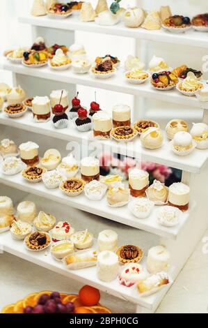 Hochzeitsempfang Stand mit Süßigkeiten, Süßigkeiten, Dessert, Cupcakes, Muffins, Kuchen, Eclare mit Blumen dekoriert Stockfoto