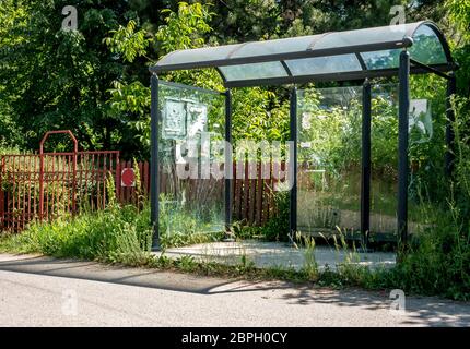 Alte verlassene Bushaltestelle mit zerbrochenem Glas, auf der Seite der Straße... Stockfoto