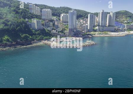 Blick von oben auf den Yachthafen mit Pier und Stadtbild von Busan mit Bergen in der Nähe von Songdo Strand Stockfoto