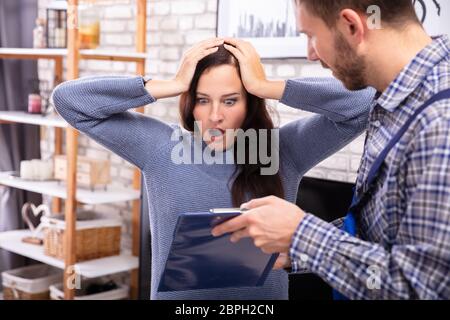 Schockiert Frau auf der Suche nach Rechnung von männlichen Techniker Stockfoto