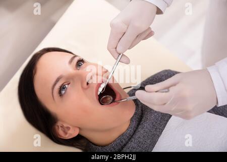 In der Nähe von Frau Zähne werden durch Zahnarzt mit zahnmedizinischer Spiegel und Scaler überprüft Stockfoto