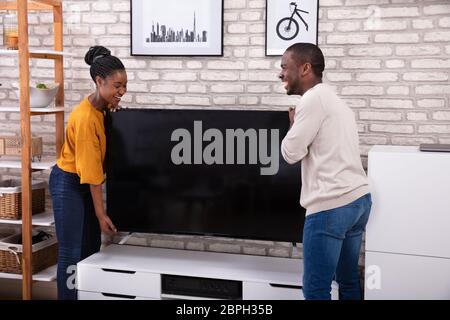 Seitenansicht des jungen afrikanischen Paar heben Fernsehen zu Hause Stockfoto