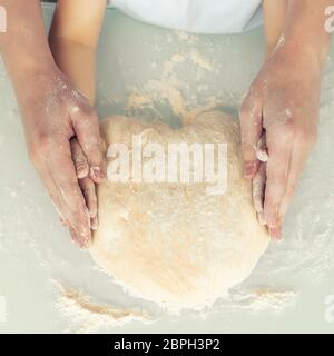 Papa und Baby Formen zusammen eine herzförmige Torte, Hände nah an. Konzept der Liebe und Familienwerte Stockfoto