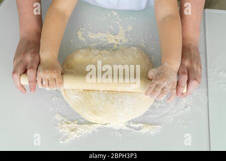 Glückliche Familie in der Küche. Mutter und Tochter Rollen den Teig mit einem Nudelholz aus. Urlaub und Familie Freizeitkonzept. Stockfoto