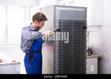 Soldaten in insgesamt Arbeiten am Kühlschrank mit Schraubenschlüssel in der Küche Stockfoto