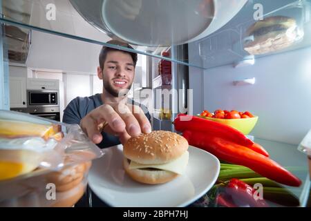 Lächelnden jungen Menschen Berühren der Burger im Kühlschrank Stockfoto