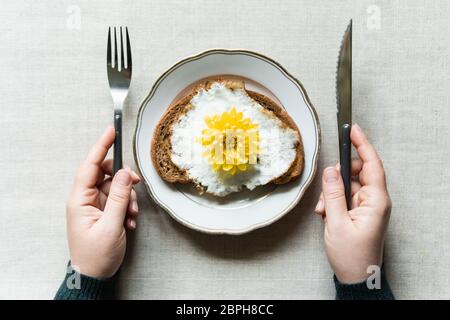 Konzeptionelles Bild des Frühstücks mit Spiegelei Toast. Gelbe Chrysanthemum Blume statt Dotter serviert auf einem weißen Teller Stockfoto