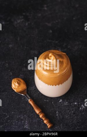 Draufsicht auf ein Glas mit cremigem und schaumig geschlagenen Kaffee Dalgona auf schwarzem Hintergrund Stockfoto