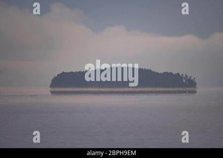 Insel Erscheinen aus dem Morgennebel am See in Saganaga Quetico Provincial Park in Ontario Stockfoto