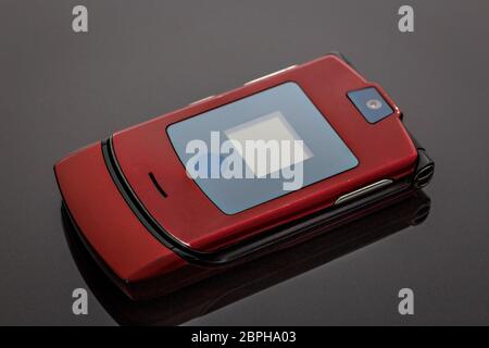 Altes, zerschlafenes und zerkratztes Mobiltelefon auf grauem Hintergrund mit Spiegelung Stockfoto