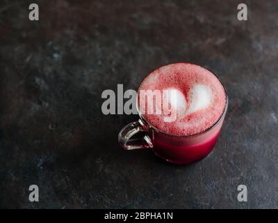 Trendgetränk: Pink Red velvet Latte. Rote Beete Cappuccino oder Latte in Glas Schale auf schwarzen Hintergrund. Kopieren Sie Platz für Text. Stockfoto