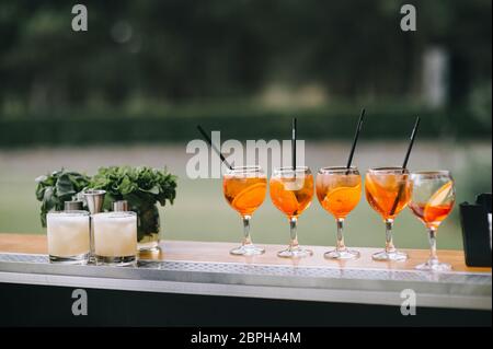 Vier Gläser aperol Spritz mit Stroh für Cocktails stehen auf einer Theke. Stockfoto