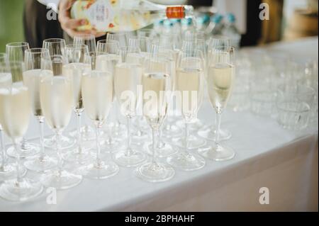 Viele Gläser mit Champagner liegen auf dem Tisch. Der Tisch ist mit einer weißen Tischdecke bedeckt Stockfoto