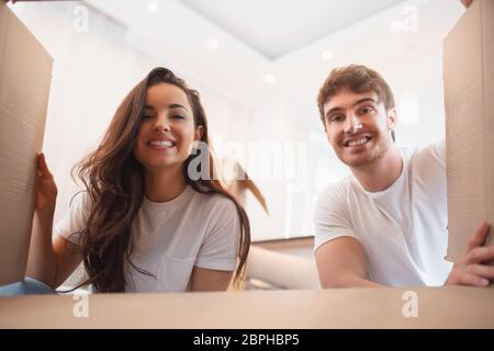 Junges Paar schaut in die Box. Glückliche junge Mann und Frau Auspacken oder Verpackung Kisten und Umzug in ein neues Zuhause Stockfoto