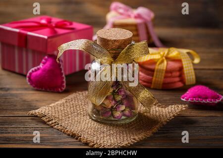 Rose buds Tee im Glas, Filz Herz, Geschenk und Cookies auf Hintergrund Stockfoto