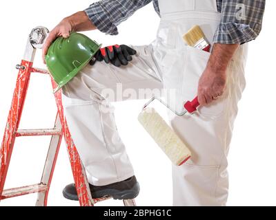 Haus Maler Arbeiter auf der Leiter mit weißen Arbeit Overalls, verhindert, dass die Walze in seiner Hand zu malen. Mit Schuhe, Helm und Handschuhe. Stockfoto