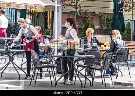 Bar und Restaurant im Freien mit Kunden und Kellnerin mit Maske und Handschuh in Vilnius, litauische Hauptstadt, die in eine große Open-Air-Café-Stadt verwandelt werden Stockfoto