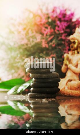 DaySpa-Massagesteine. Spa und Wellness-Umgebung. Basaltsteine in der Nähe von beruhigendem Wasser. Spa und Wellness-Produkte Stockfoto